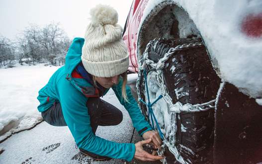 Woman installing snow tire chains on her car